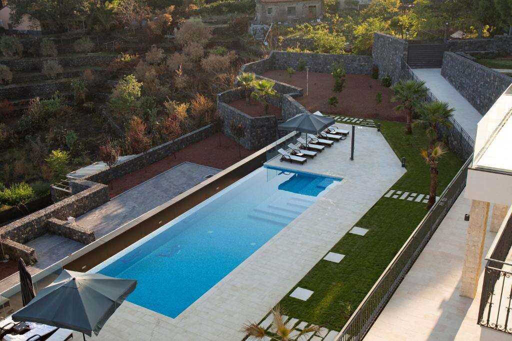 Heated infinity pool with loungers and umbrellas seen from above